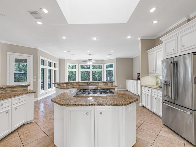 kitchen featuring stainless steel appliances, tasteful backsplash, a center island, and dark stone countertops