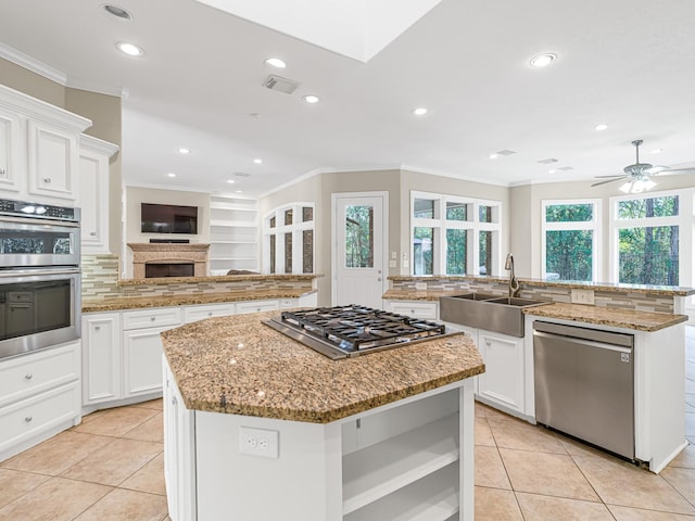 kitchen with a center island with sink, crown molding, stainless steel appliances, visible vents, and a sink