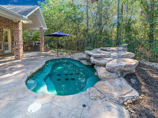 view of swimming pool featuring a patio area, a fenced backyard, exterior kitchen, and a swimming pool