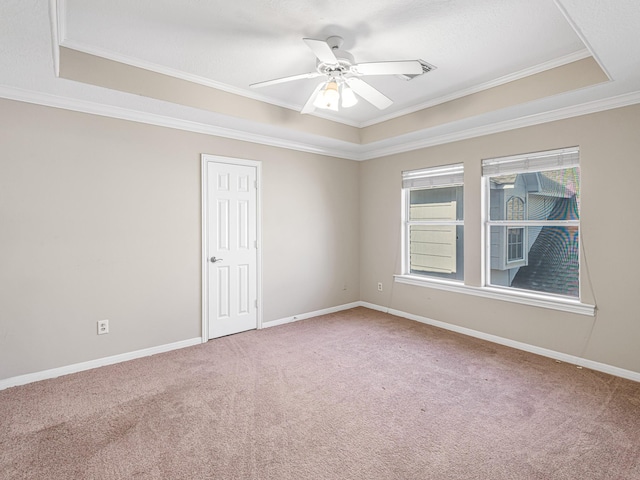 carpeted spare room with ceiling fan, ornamental molding, and a tray ceiling