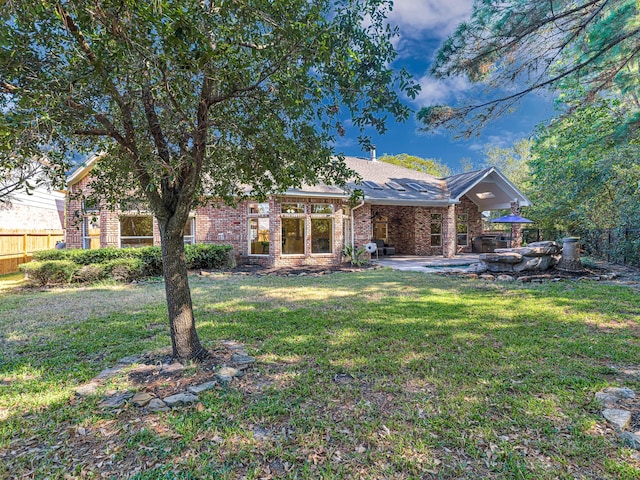 view of front of home featuring a patio area, brick siding, fence, and a front lawn