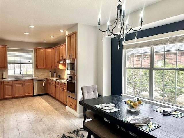 kitchen featuring a notable chandelier, decorative backsplash, sink, hanging light fixtures, and stainless steel appliances