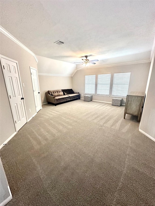 unfurnished bedroom featuring a textured ceiling, lofted ceiling, carpet floors, ceiling fan, and crown molding