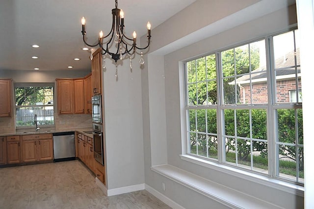 kitchen with an inviting chandelier, appliances with stainless steel finishes, decorative backsplash, hanging light fixtures, and sink