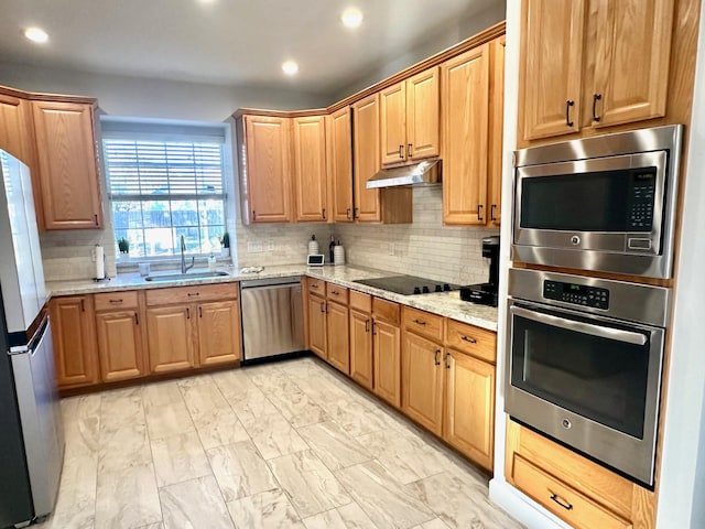 kitchen with decorative backsplash, appliances with stainless steel finishes, sink, and light stone counters