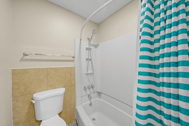 bathroom featuring toilet, shower / bathtub combination with curtain, and tile walls