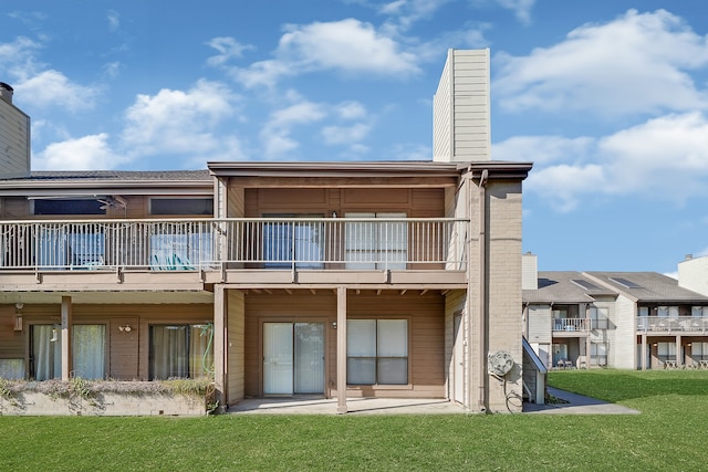 back of property with a lawn and a balcony