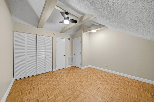 unfurnished bedroom featuring lofted ceiling with beams, a textured ceiling, light parquet flooring, and ceiling fan