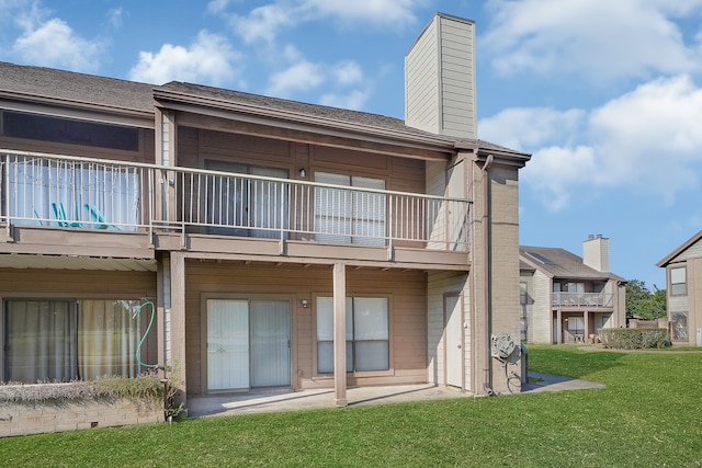 rear view of house featuring a balcony and a lawn