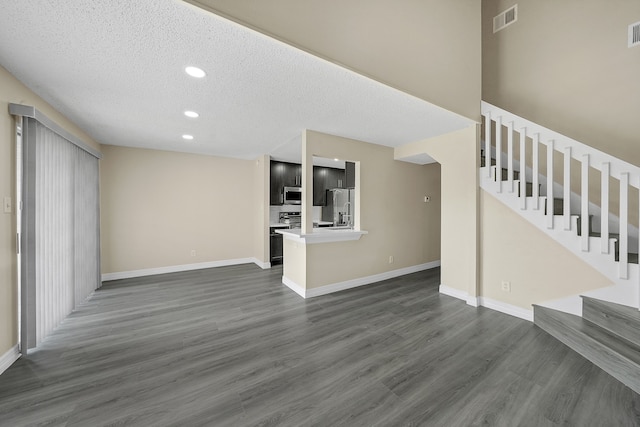 unfurnished living room with dark wood-type flooring and a textured ceiling