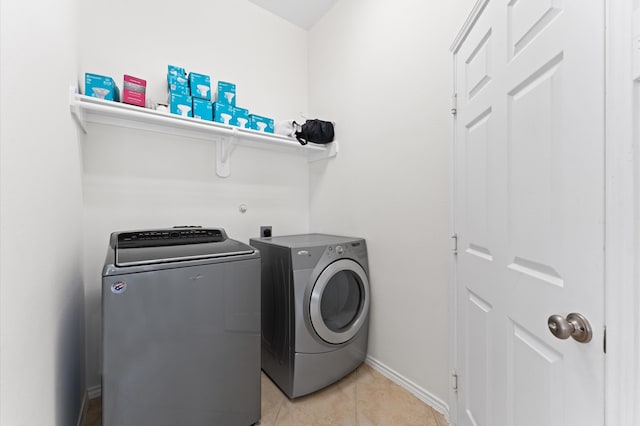 laundry area with separate washer and dryer and light tile patterned floors