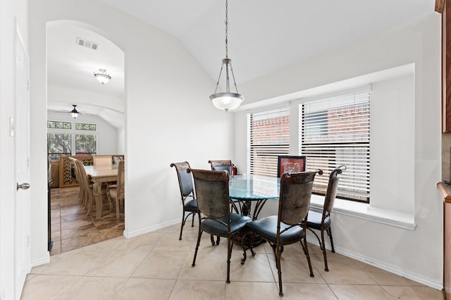 tiled dining space with ceiling fan and vaulted ceiling