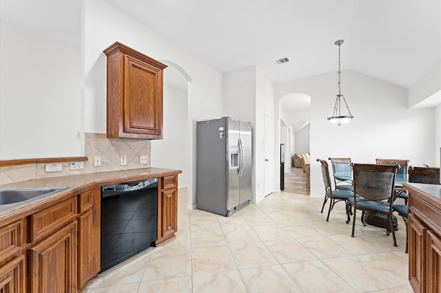 kitchen featuring dishwasher, hanging light fixtures, stainless steel fridge, light tile patterned floors, and tasteful backsplash