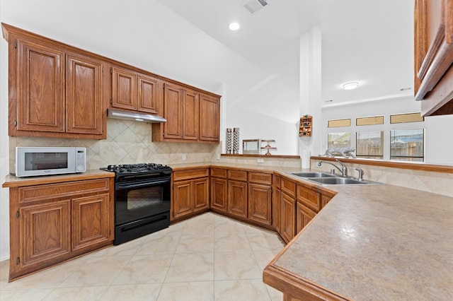 kitchen with black stove, kitchen peninsula, backsplash, sink, and light tile patterned floors