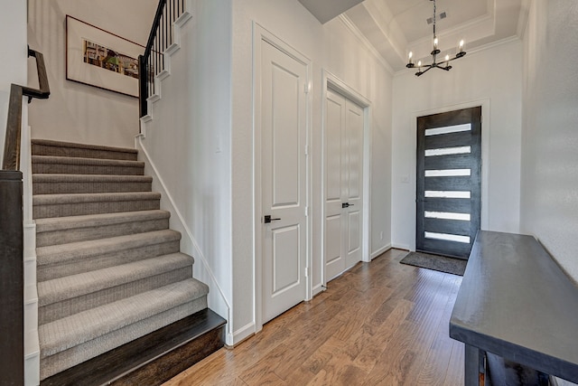 foyer with an inviting chandelier, crown molding, and wood-type flooring