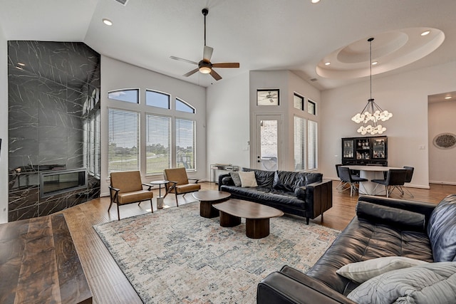 living room with high vaulted ceiling, wood-type flooring, and ceiling fan with notable chandelier