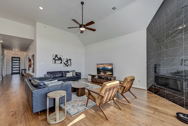 living room featuring ceiling fan, hardwood / wood-style flooring, high vaulted ceiling, and a high end fireplace