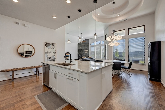 kitchen with dishwasher, sink, decorative light fixtures, white cabinets, and a kitchen island with sink