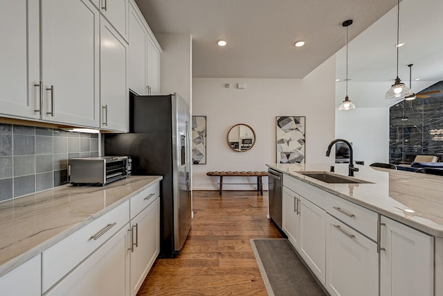 kitchen featuring sink, white cabinetry, stainless steel appliances, pendant lighting, and dark hardwood / wood-style floors