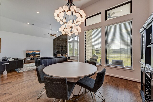 dining room with lofted ceiling, ceiling fan with notable chandelier, and hardwood / wood-style floors