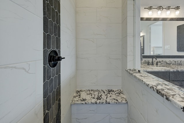 bathroom featuring a tile shower and vanity