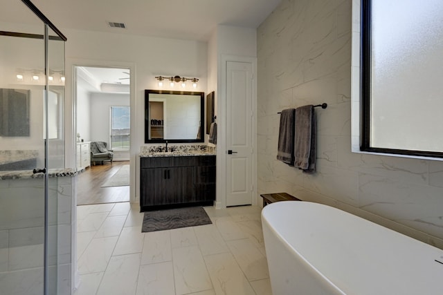 bathroom featuring vanity, tile walls, and separate shower and tub