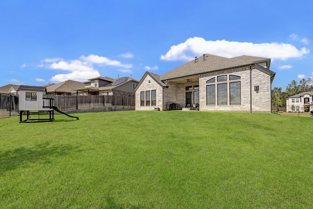 rear view of property featuring a shed and a yard