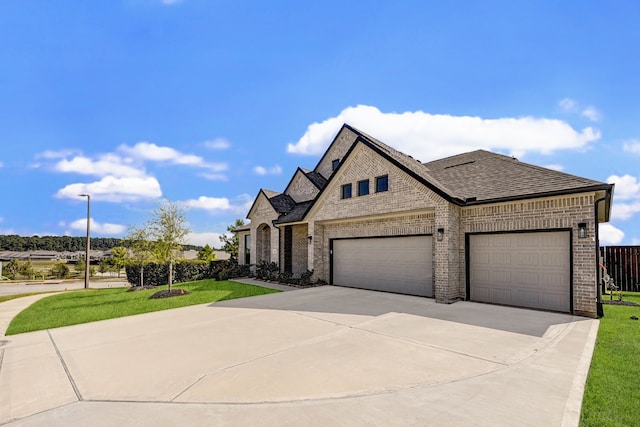 french country style house with a front yard and a garage