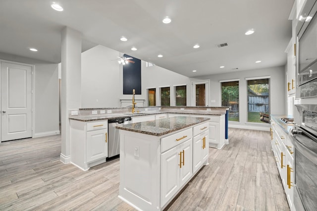 kitchen featuring a center island, kitchen peninsula, dark stone countertops, white cabinets, and appliances with stainless steel finishes