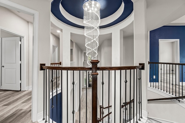 hallway with hardwood / wood-style flooring, a notable chandelier, and a raised ceiling