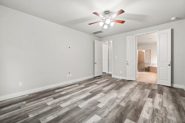 unfurnished bedroom with ceiling fan, wood-type flooring, and connected bathroom