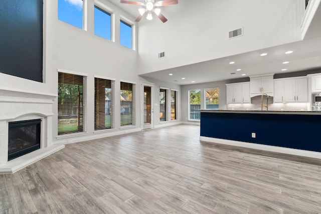 unfurnished living room featuring ceiling fan and a towering ceiling