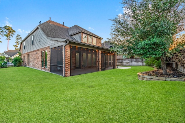 rear view of property featuring a yard and a sunroom