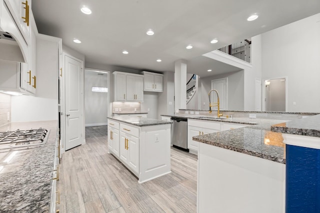 kitchen featuring appliances with stainless steel finishes, sink, dark stone countertops, white cabinets, and a large island