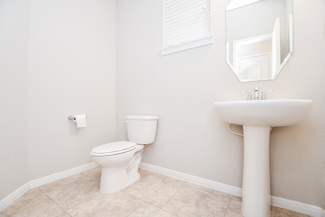 bathroom with toilet, tile patterned floors, and sink