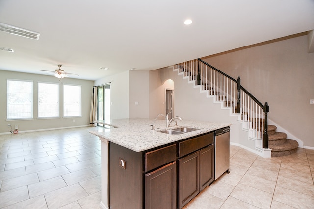 kitchen with a kitchen island with sink, dishwasher, light tile patterned flooring, dark brown cabinetry, and sink