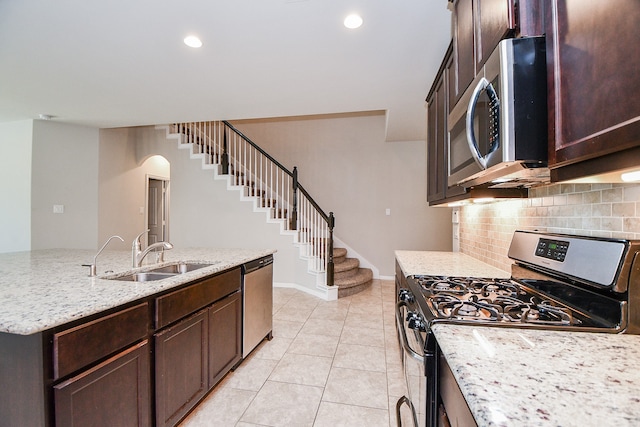 kitchen with decorative backsplash, stainless steel appliances, sink, light stone countertops, and light tile patterned floors