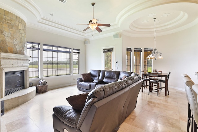 living room featuring ceiling fan with notable chandelier, a large fireplace, a raised ceiling, and ornamental molding