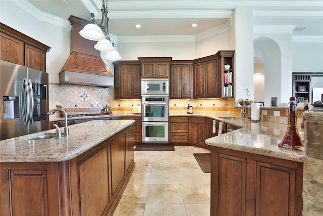 kitchen featuring kitchen peninsula, decorative backsplash, appliances with stainless steel finishes, light stone counters, and decorative light fixtures