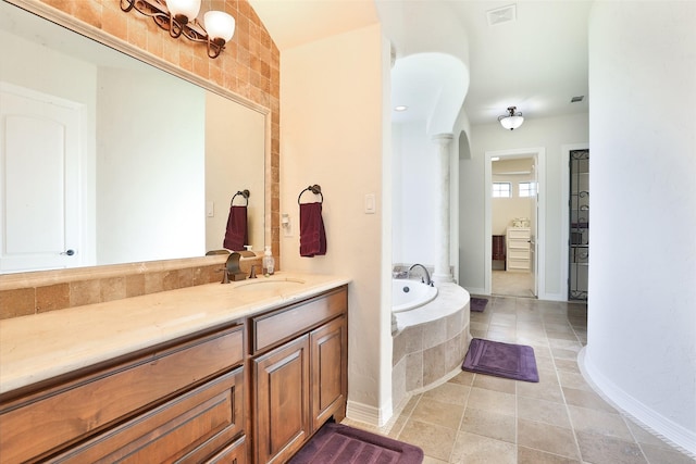 bathroom featuring tile patterned flooring, vanity, and tiled bath