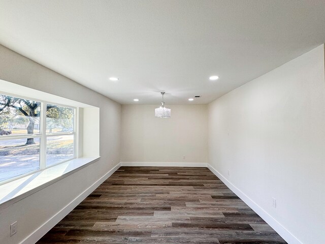 unfurnished room with a chandelier and dark hardwood / wood-style floors