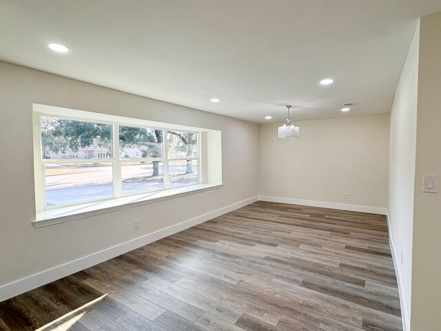 unfurnished room with an inviting chandelier and hardwood / wood-style floors