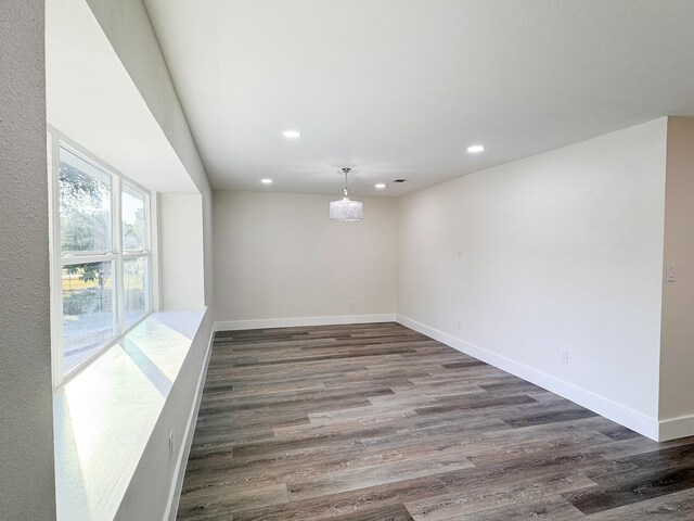 empty room featuring dark wood-type flooring and a chandelier