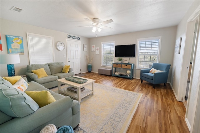 living room with light hardwood / wood-style flooring, a textured ceiling, and ceiling fan