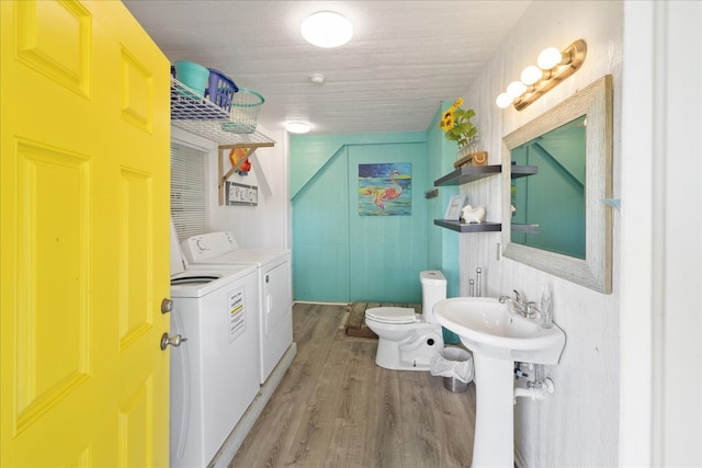 bathroom featuring washing machine and dryer, toilet, and hardwood / wood-style flooring