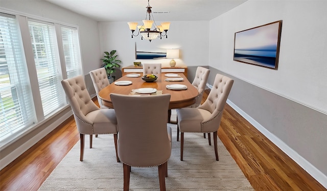 dining area featuring hardwood / wood-style flooring, a healthy amount of sunlight, and an inviting chandelier