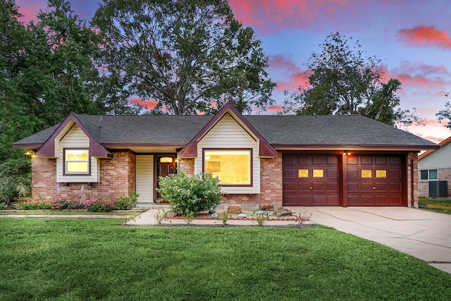 ranch-style home with central AC unit, a garage, and a lawn