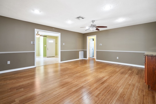 empty room with ceiling fan, a textured ceiling, and light wood-type flooring