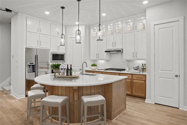 kitchen with sink, stainless steel appliances, light hardwood / wood-style floors, an island with sink, and white cabinets