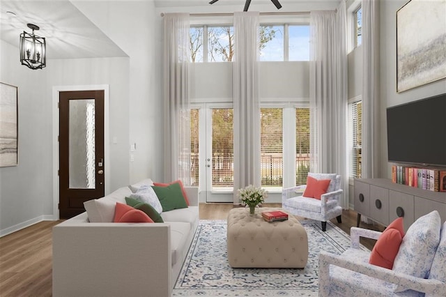 living room with hardwood / wood-style flooring, a towering ceiling, and a chandelier